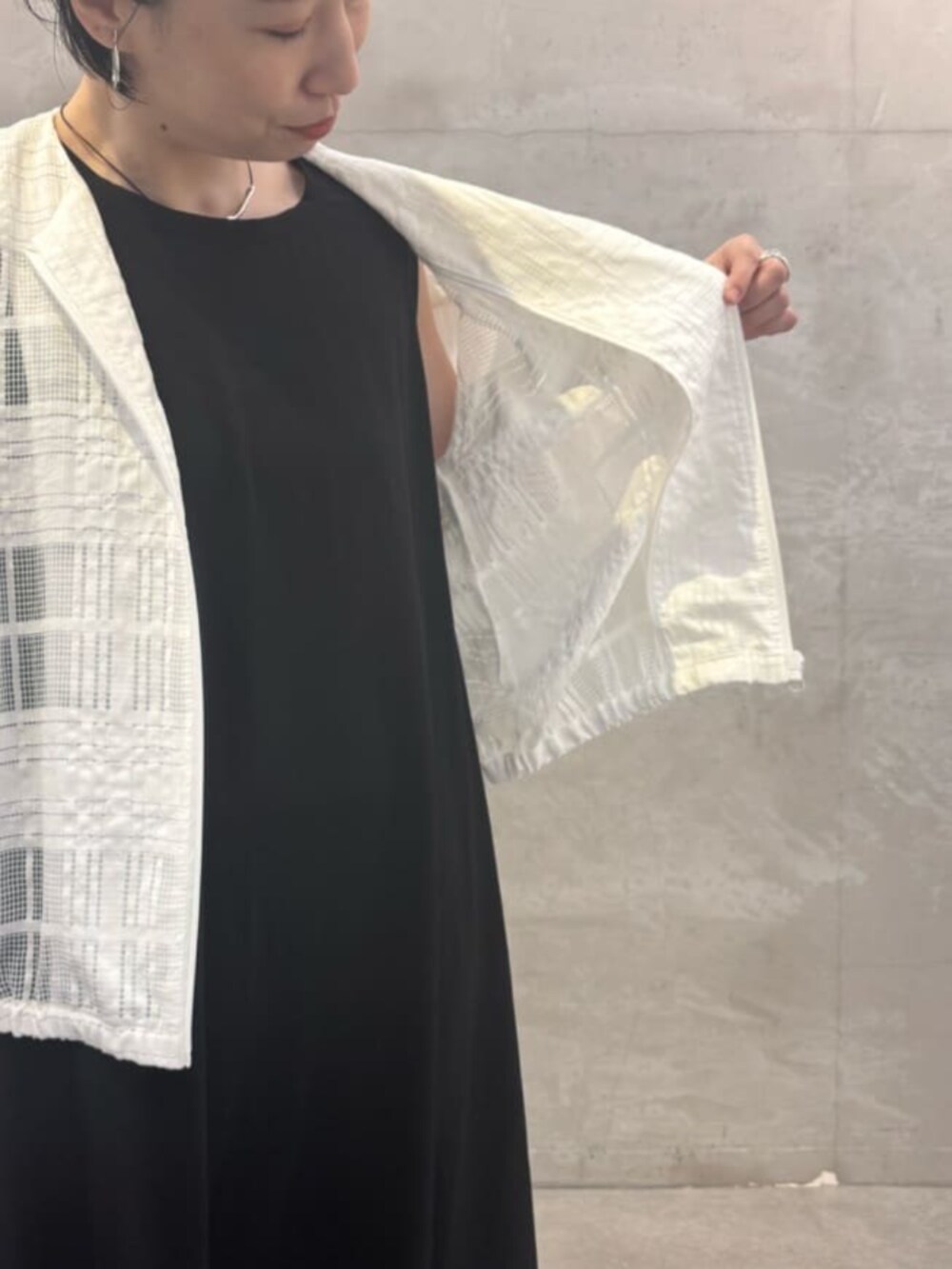 グレー系のハンドバッグ、ブラック系のワンピース、ホワイト系のブルゾンを着用したレディースの夏コーディネートの7枚目の写真