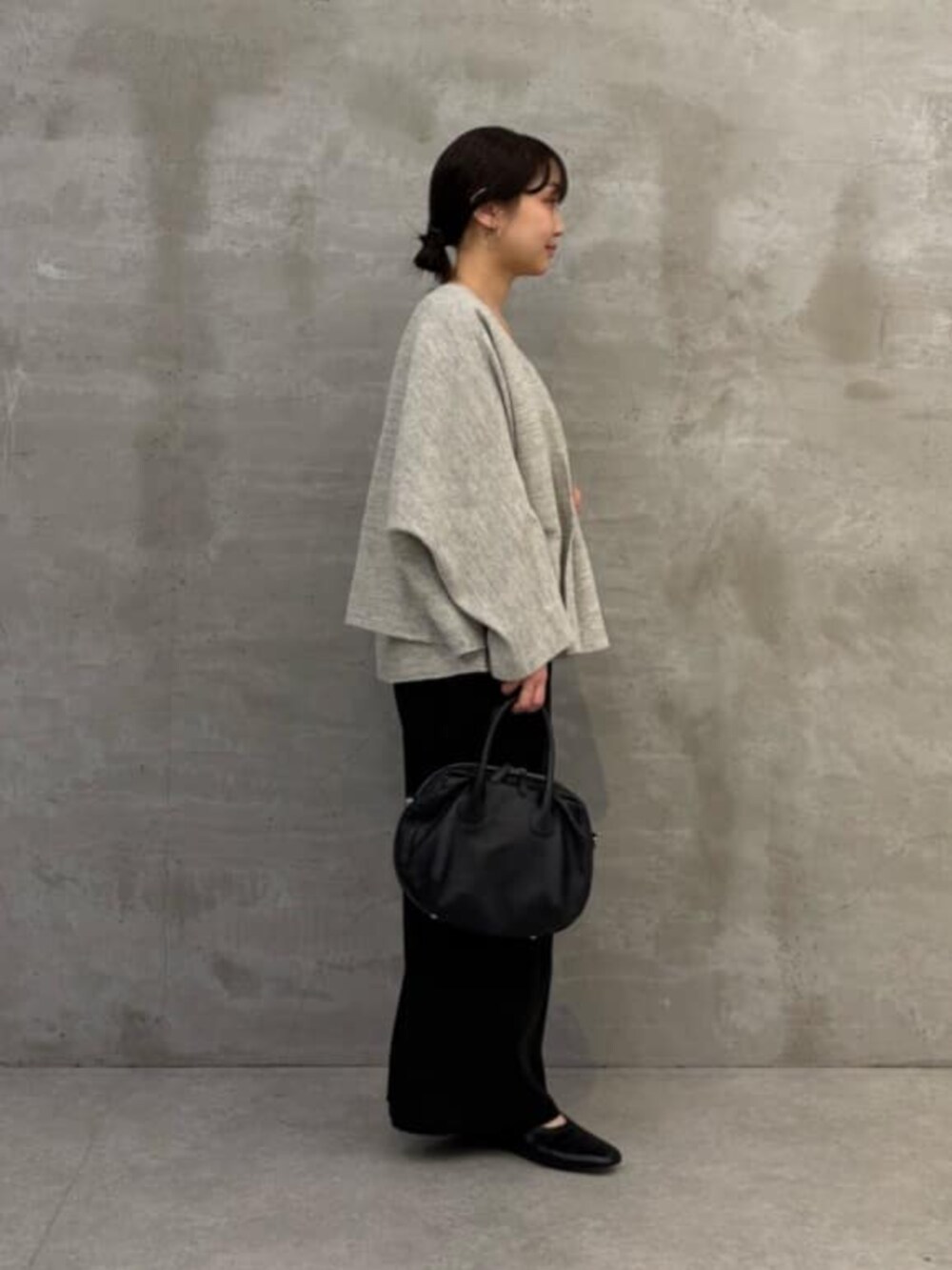 ブラック系のボストンバッグ、グレー系のニット/セーター、グレー系のカーディガン/ボレロを着用したレディースの春コーディネートの7枚目の写真