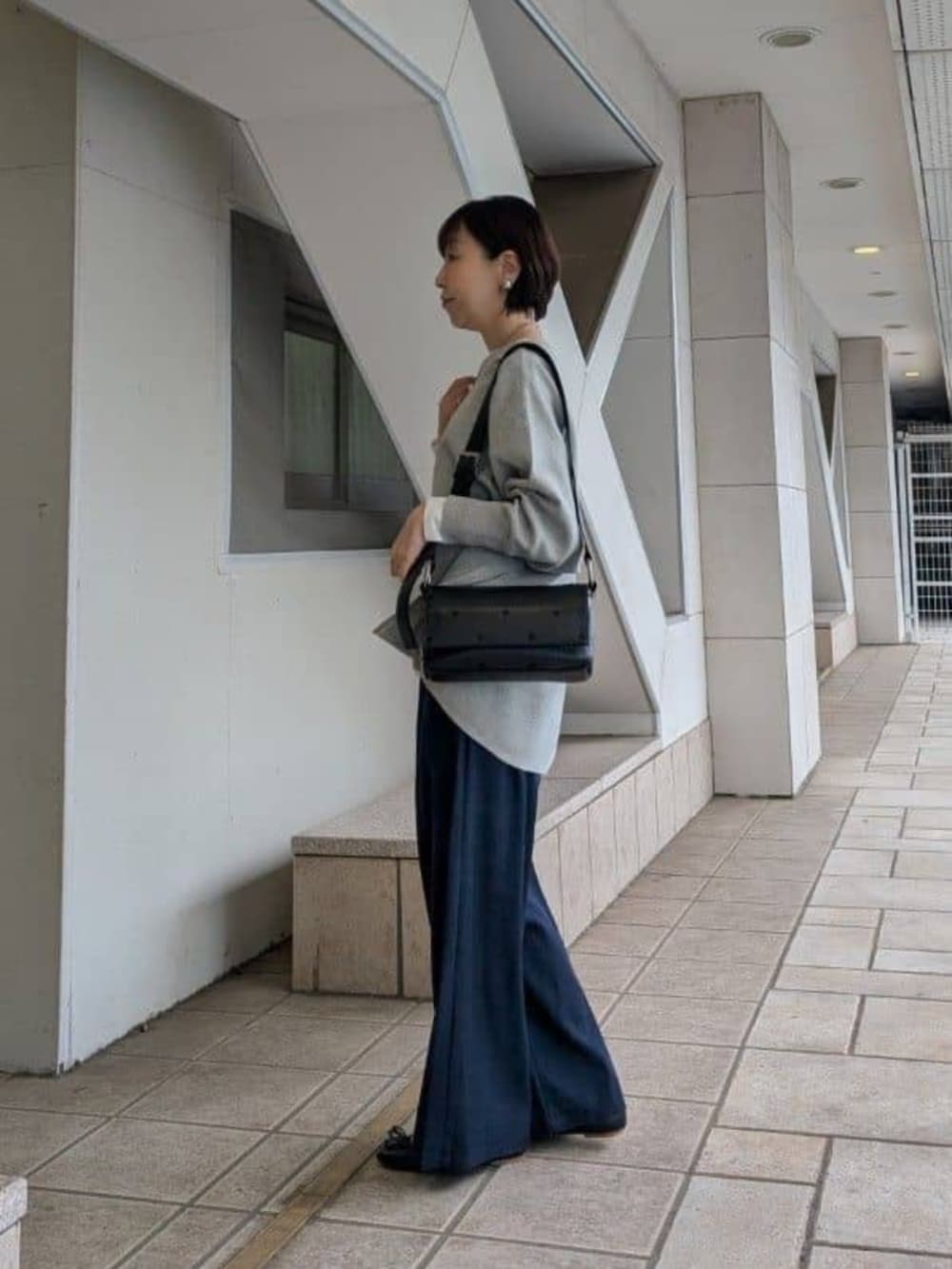 ブルー系のその他パンツ、グレー系のニット/セーター、ホワイト系のノーカラージャケットを着用したレディースの冬コーディネートの6枚目の写真