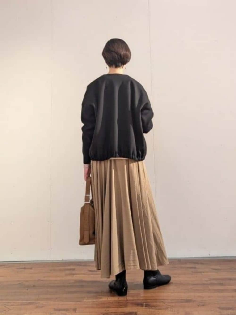 ブラウン系のスカート、ブラック系のブルゾンを着用したレディースの秋コーディネートの3枚目の写真