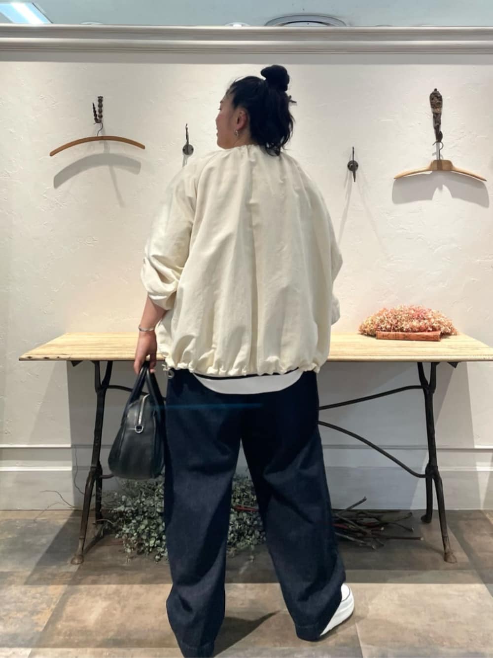 ホワイト系のノーカラージャケット、ホワイト系のニット/セーター、ブルー系のデニムパンツを着用したレディースの冬コーディネートの4枚目の写真