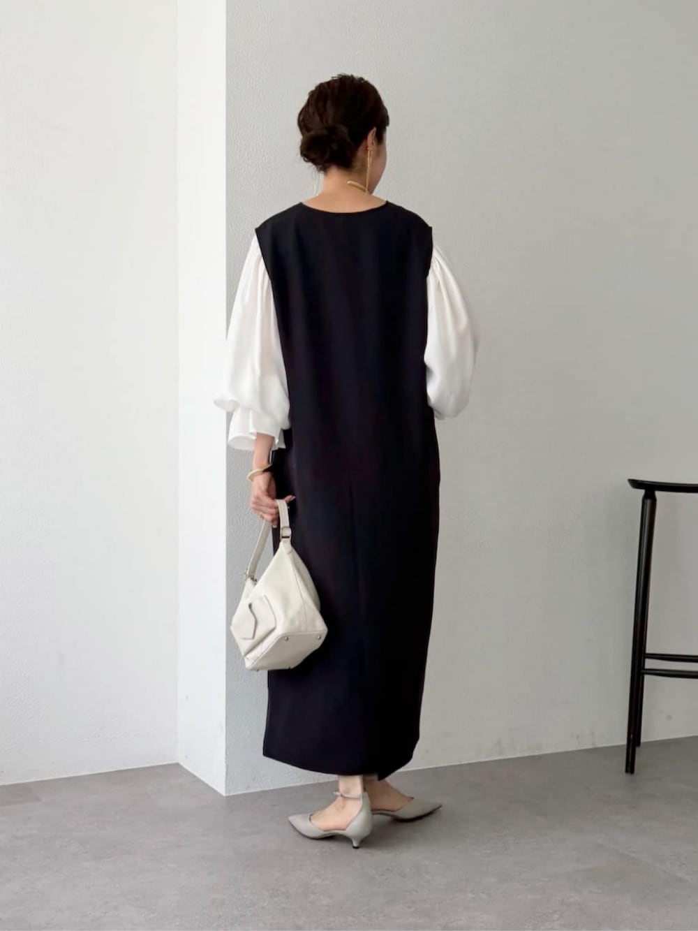ホワイト系のシャツ/ブラウス、ブラック系のジャンパースカート、グレー系のパンプスを着用したレディースの秋コーディネートの3枚目の写真