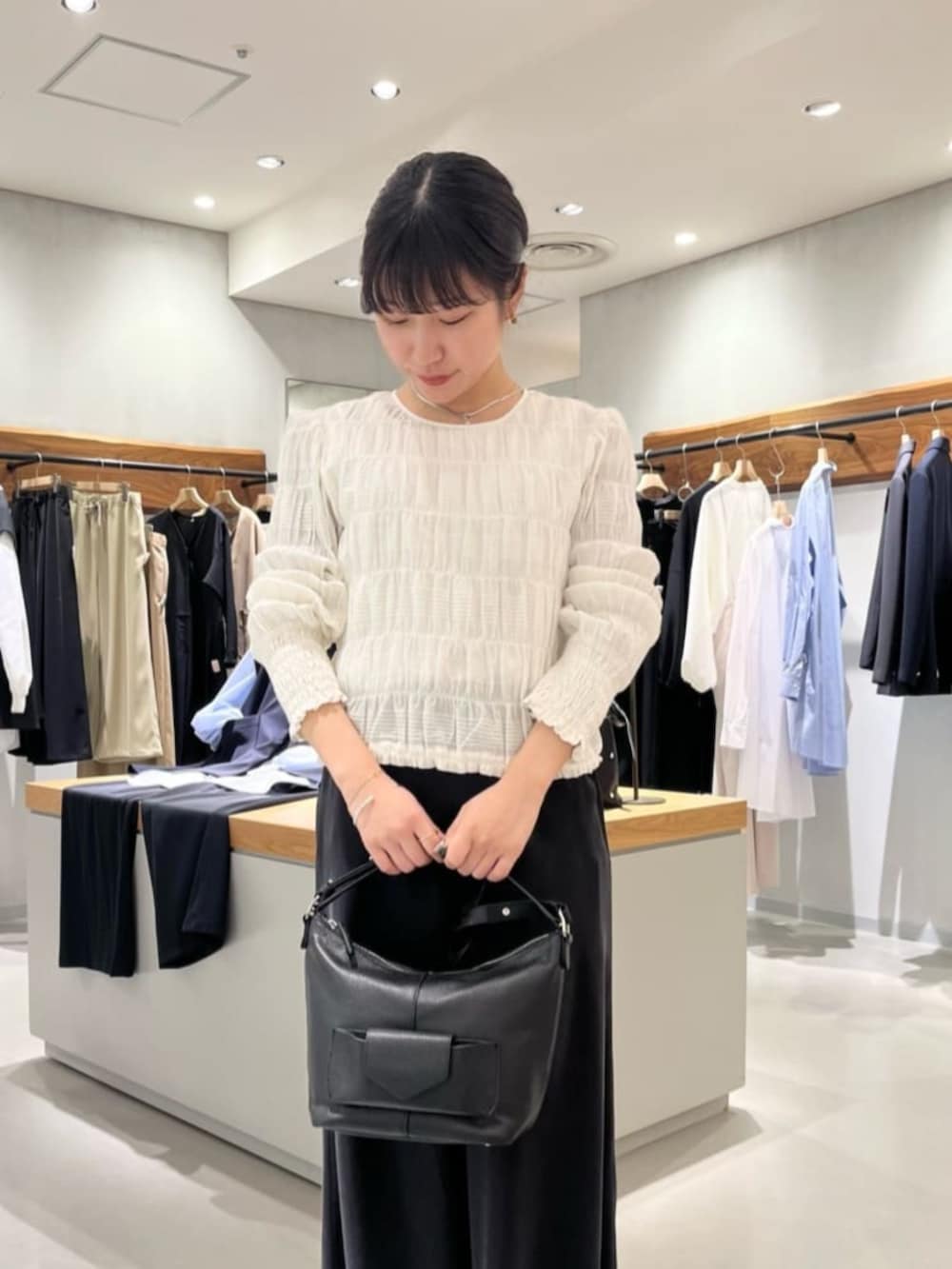 ブラック系のスカート、ブラック系のトートバッグ、ホワイト系のシャツ/ブラウスを着用したレディースの春コーディネートの5枚目の写真