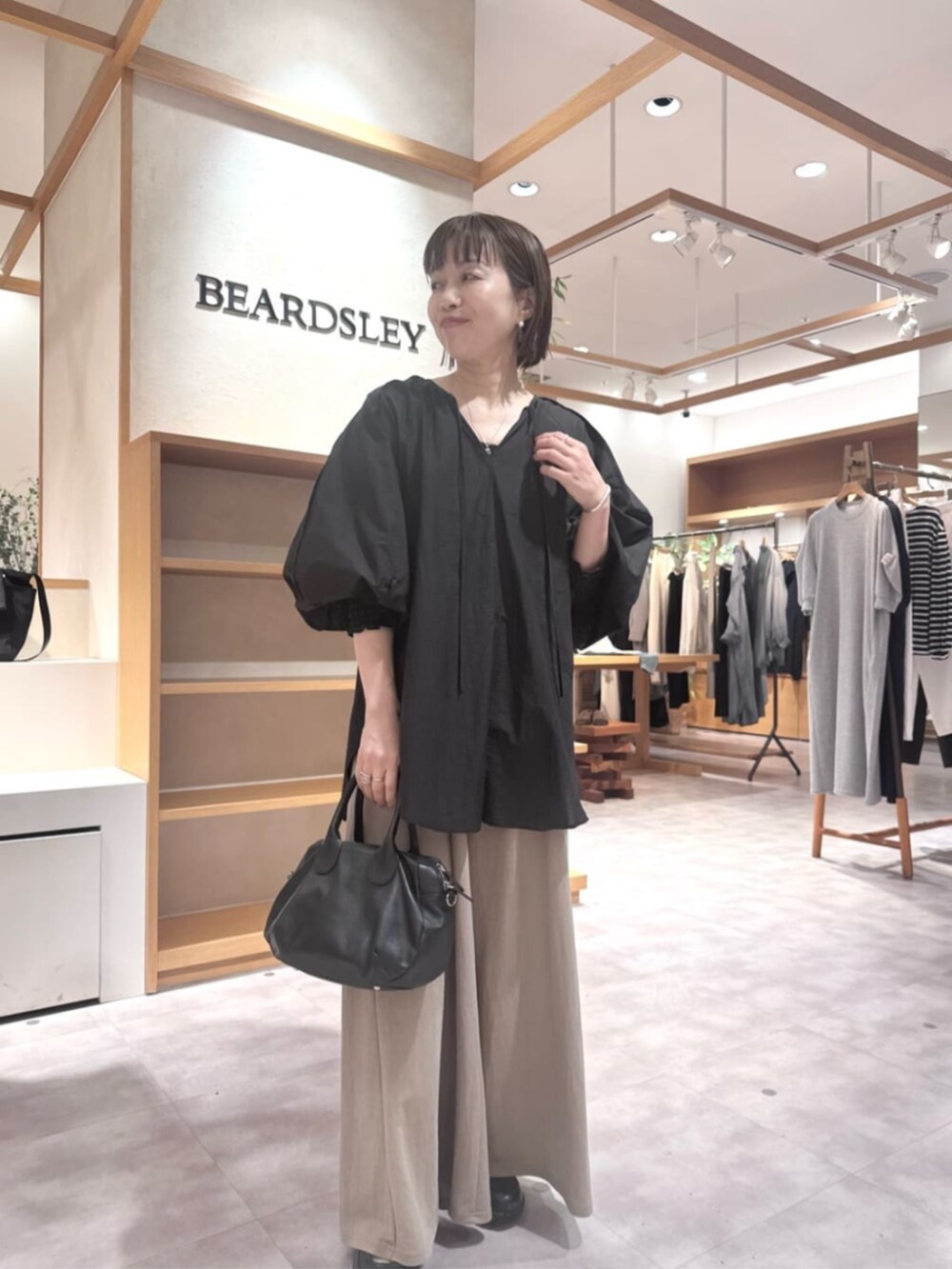 ブラック系のボストンバッグ、ベージュ系のその他パンツ、ブラック系のシャツ/ブラウスを着用したレディースの春コーディネートの2枚目の写真