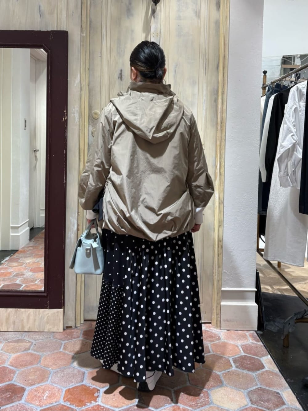 グリーン系のハンドバッグ、ブラック系のスカート、ブラウン系のブルゾンを着用したレディースの冬コーディネートの3枚目の写真