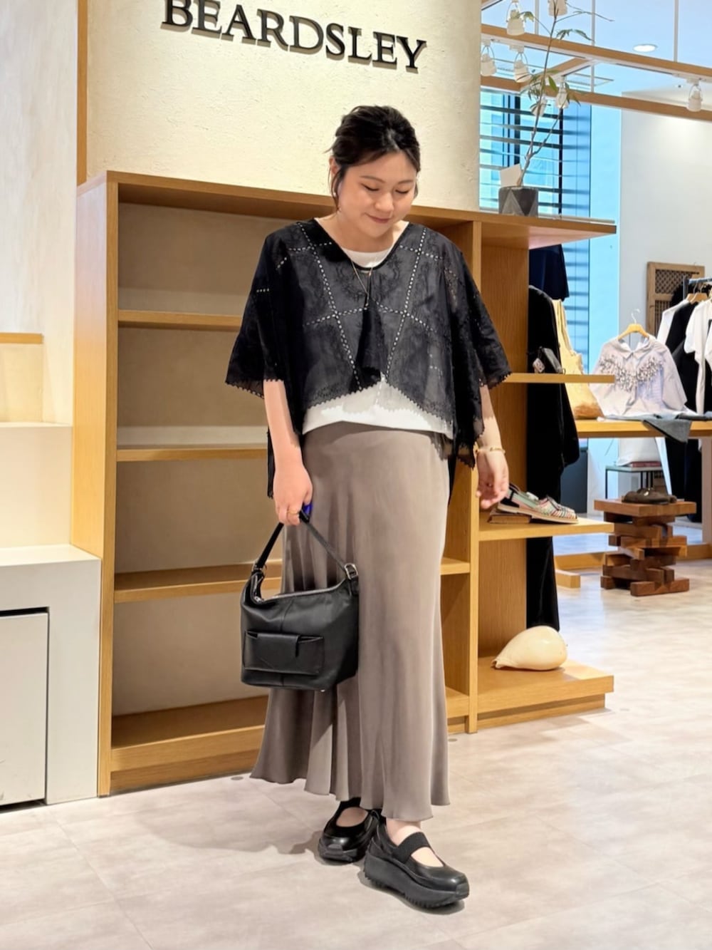 グリーン系のスカート、ブラック系のシャツ/ブラウス、ブラック系のスニーカーを着用したレディースの春コーディネートの2枚目の写真