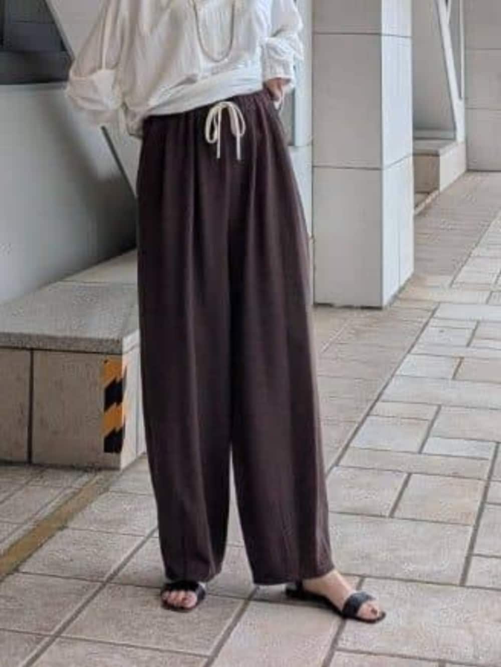 グレー系のハンドバッグ、ホワイト系のTシャツ/カットソー、ブラウン系のその他パンツを着用したレディースの夏コーディネートの7枚目の写真