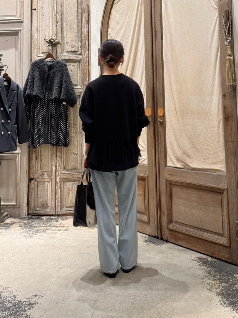 ブルー系のデニムパンツ、ブラウン系のトートバッグ、ブラック系のカーディガン/ボレロを着用したレディースの冬コーディネートの2枚目の写真