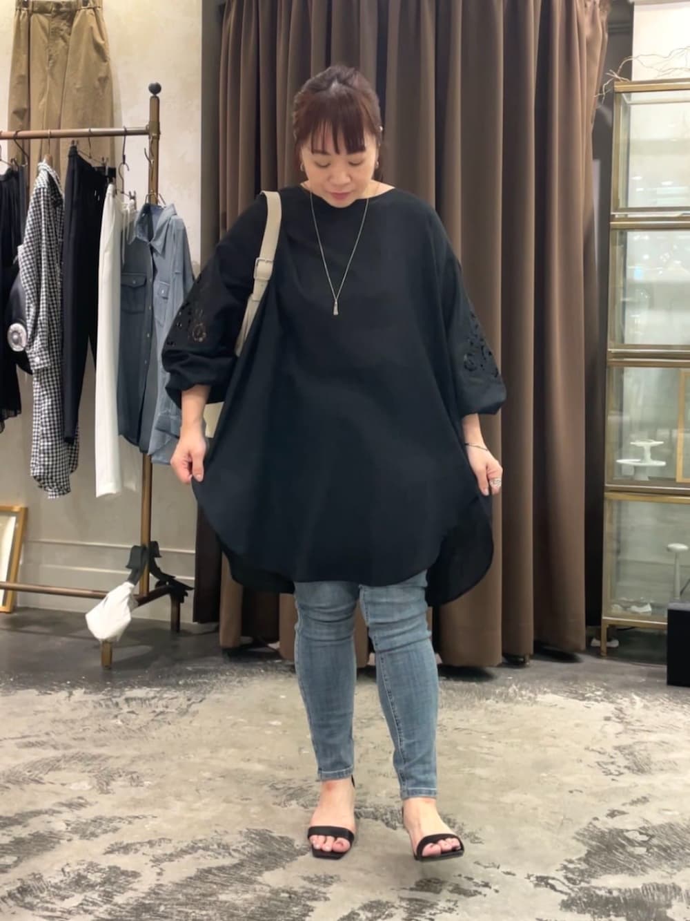 ブルー系のデニムパンツ、ホワイト系のショルダーバッグ、ブラック系のシャツ/ブラウスを着用したレディースの春コーディネートの4枚目の写真