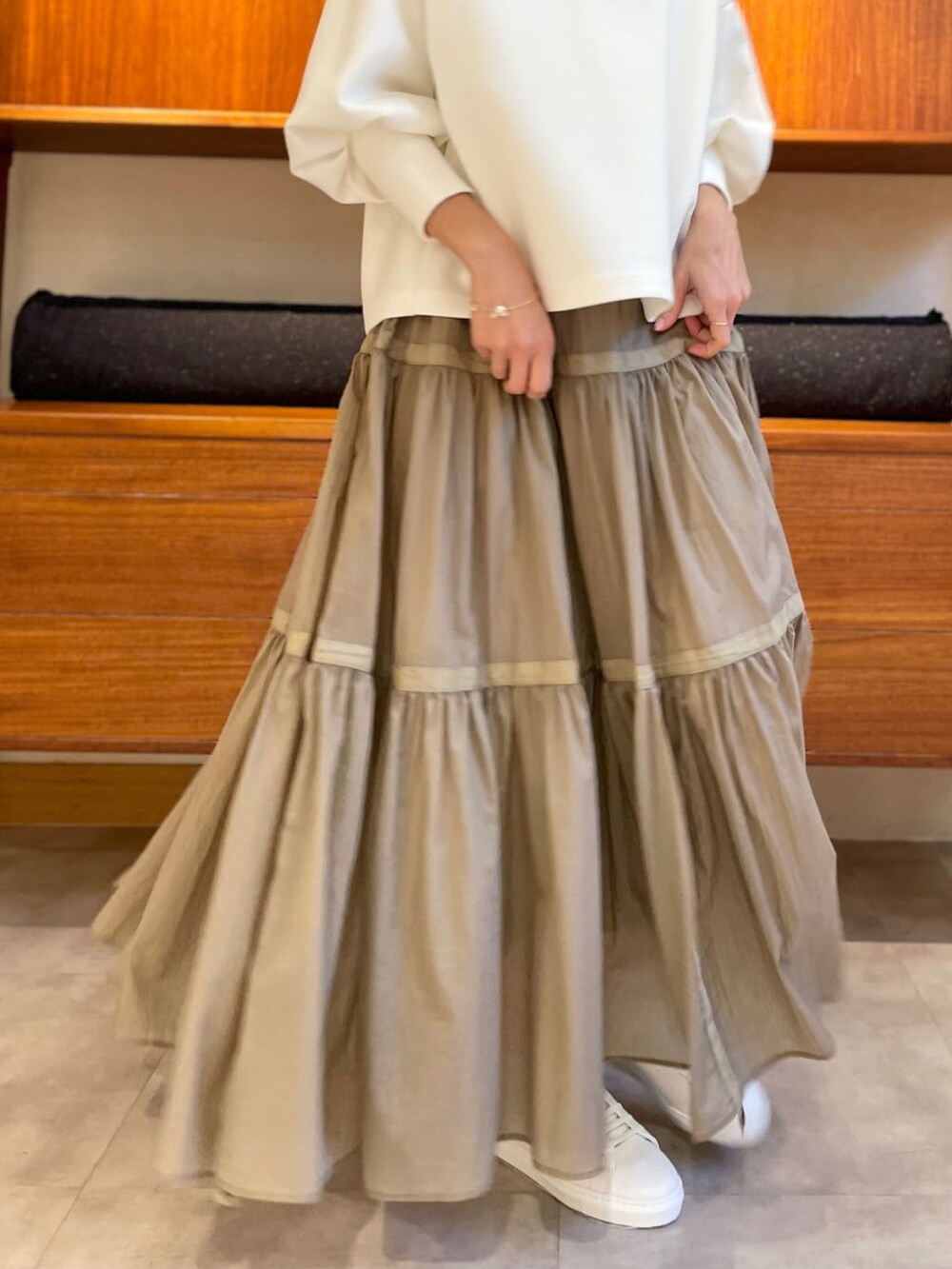 ホワイト系のTシャツ/カットソー、ベージュ系のスカート、ホワイト系のスニーカーを着用したレディースの冬コーディネートの3枚目の写真