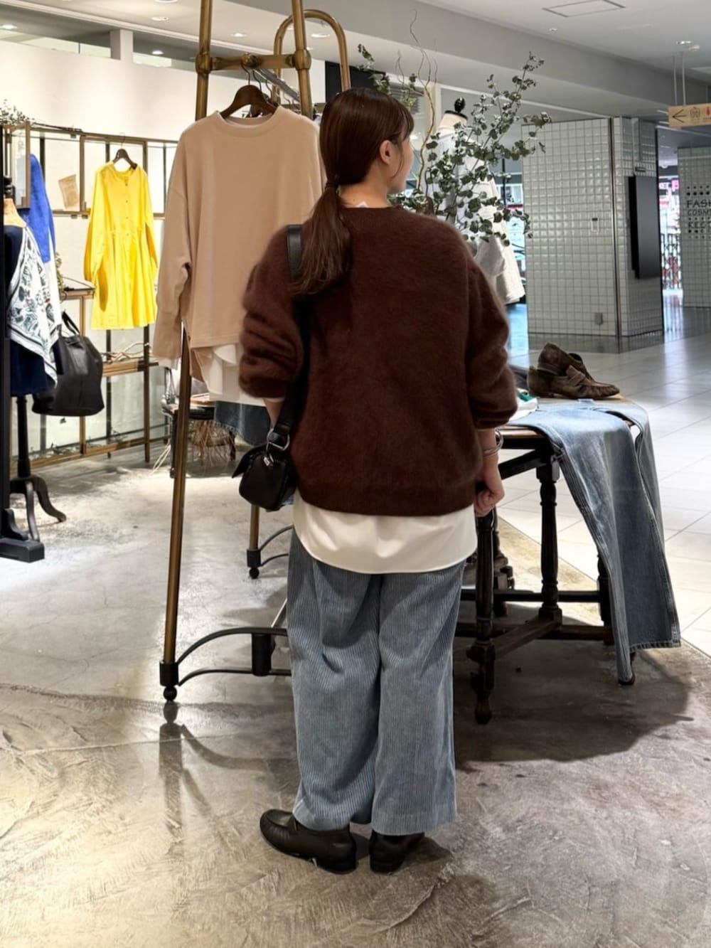 ブラック系のショルダーバッグ、ブラウン系のニット/セーター、ブルー系のその他パンツを着用したレディースの秋コーディネートの4枚目の写真