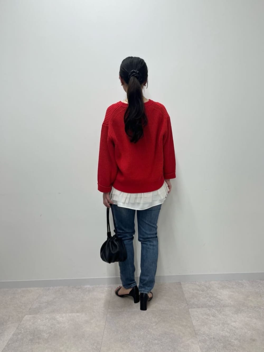 ブルー系のデニムパンツ、ホワイト系のタンクトップ、レッド系のニット/セーターを着用したレディースの冬コーディネートの6枚目の写真