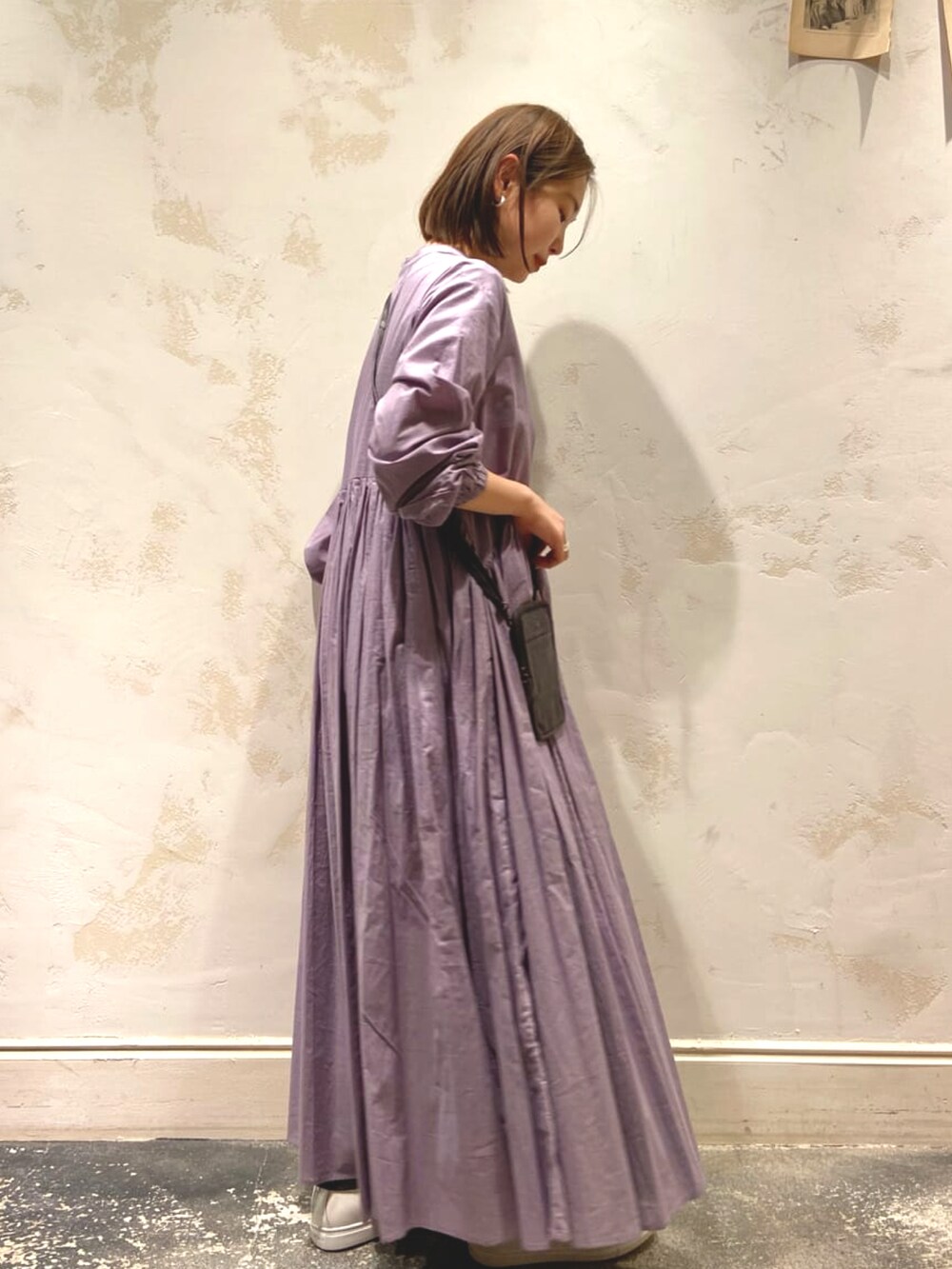 グレー系のワンピース、ブラック系のショルダーバッグ、ホワイト系のスニーカーを着用したレディースの冬コーディネートの2枚目の写真