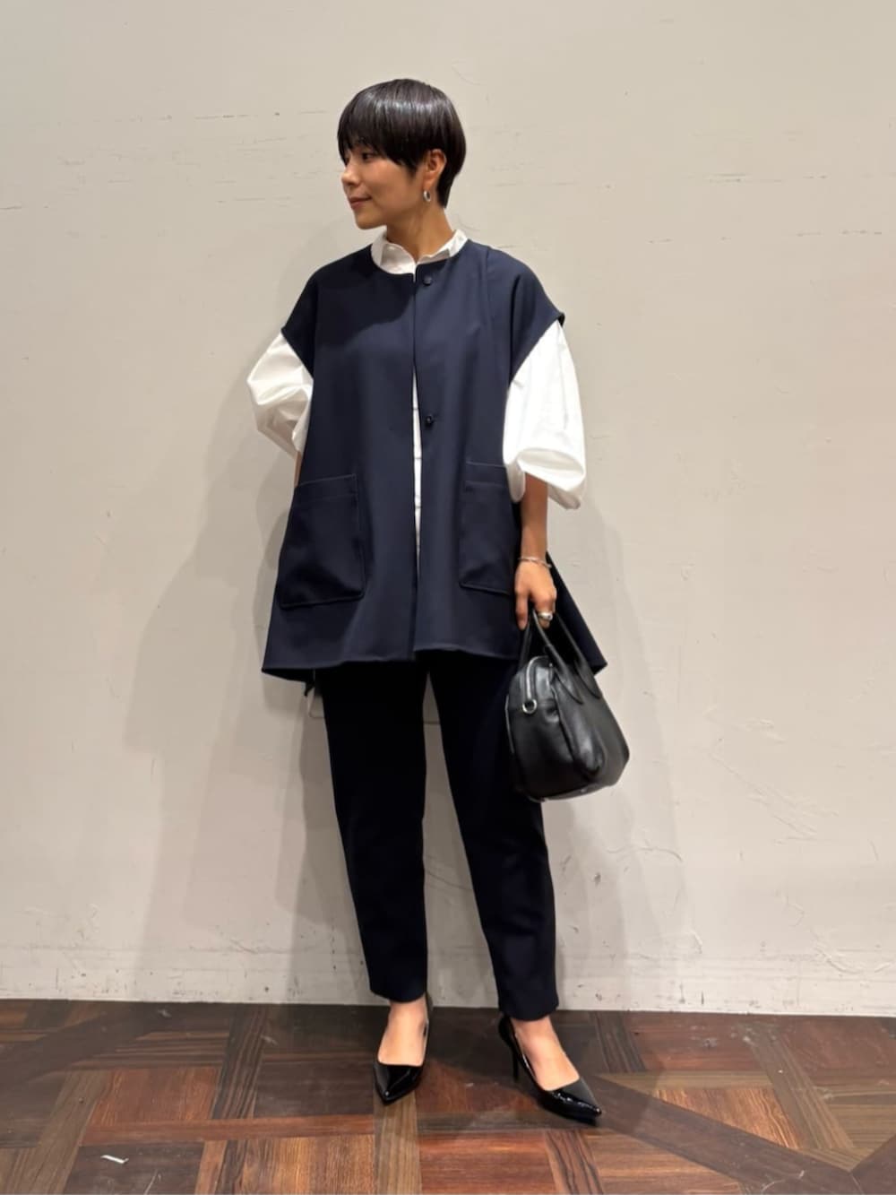 ブラック系のボストンバッグ、ブルー系のベスト、ホワイト系のシャツ/ブラウスを着用したレディースの冬コーディネートの2枚目の写真