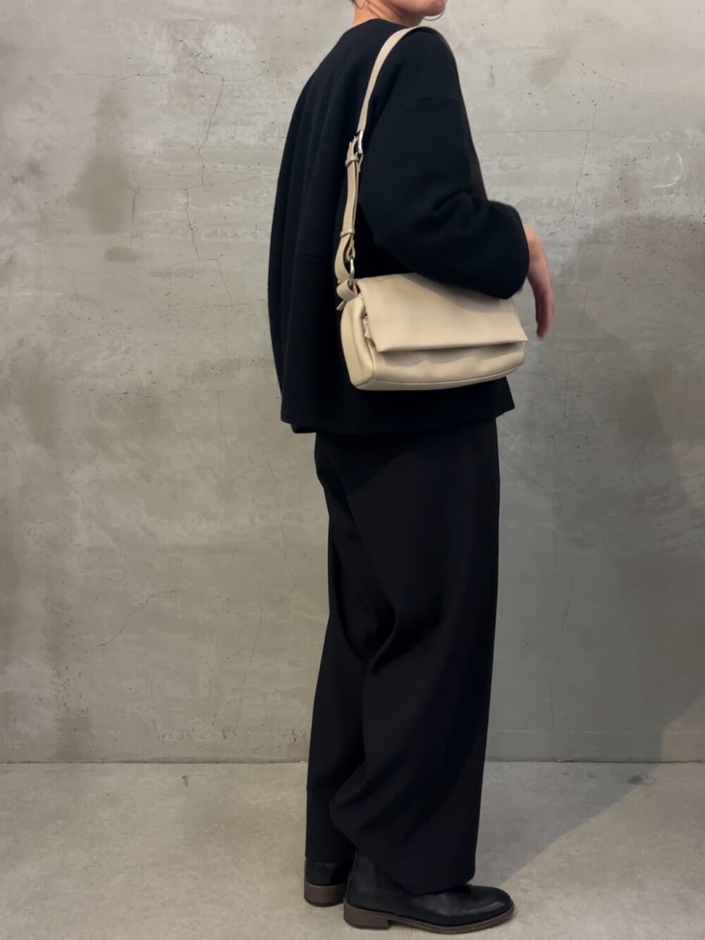 ブラック系のノーカラーコート、ブラック系のその他パンツ、ホワイト系のショルダーバッグを着用したレディースの冬コーディネートの3枚目の写真