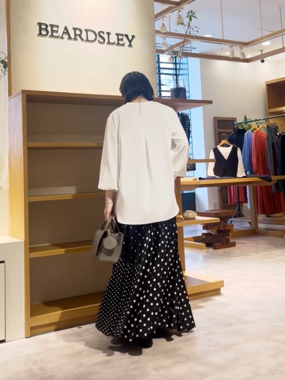 ブラック系のスカート、グレー系のハンドバッグ、ホワイト系のシャツ/ブラウスを着用したレディースの春コーディネートの4枚目の写真