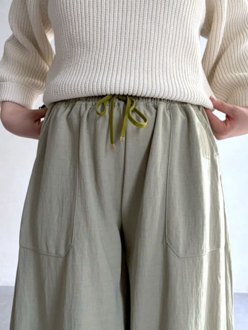 ホワイト系のニット/セーター、グリーン系のその他パンツ、ブラック系のトートバッグを着用したレディースの冬コーディネートの8枚目の写真