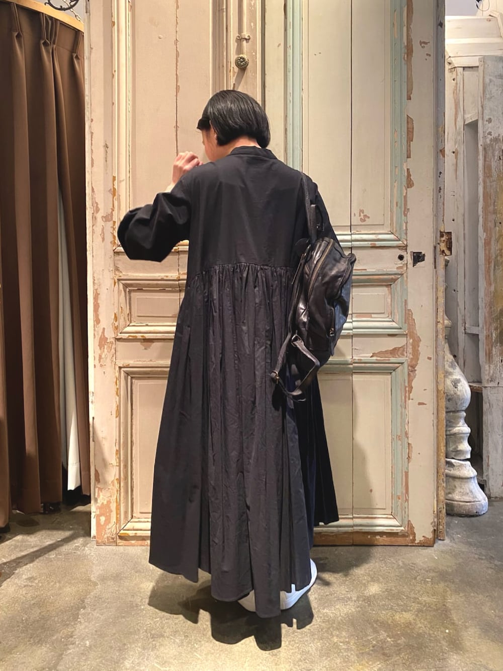 ブラック系のワンピース、ブラック系のトートバッグ、ホワイト系のスニーカーを着用したレディースの冬コーディネートの3枚目の写真