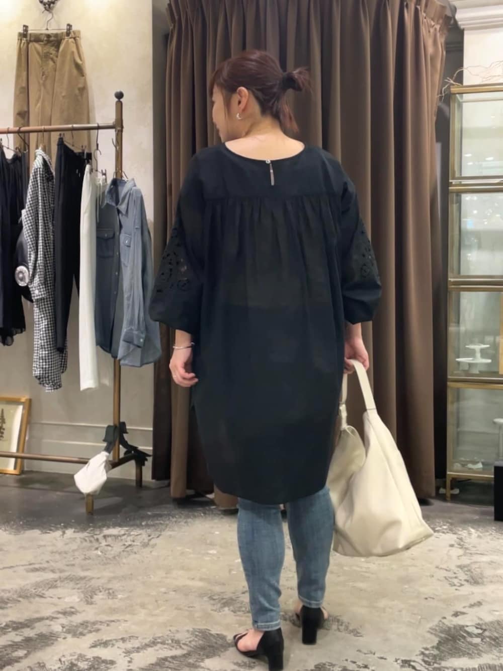 ブルー系のデニムパンツ、ホワイト系のショルダーバッグ、ブラック系のシャツ/ブラウスを着用したレディースの春コーディネートの3枚目の写真