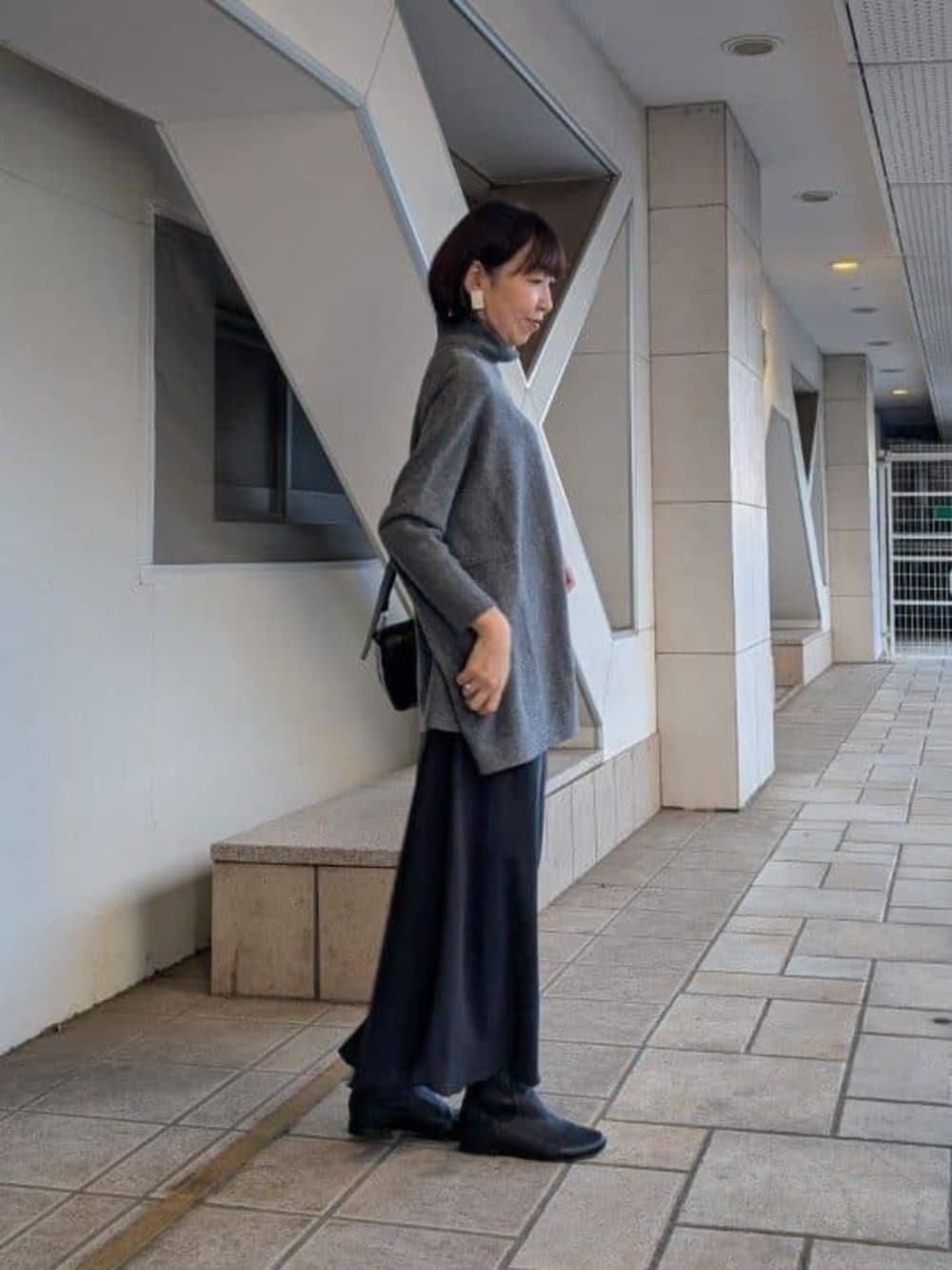 ブラック系のスカート、グレー系のニット/セーター、ブラック系のショルダーバッグを着用したレディースの冬コーディネートの3枚目の写真