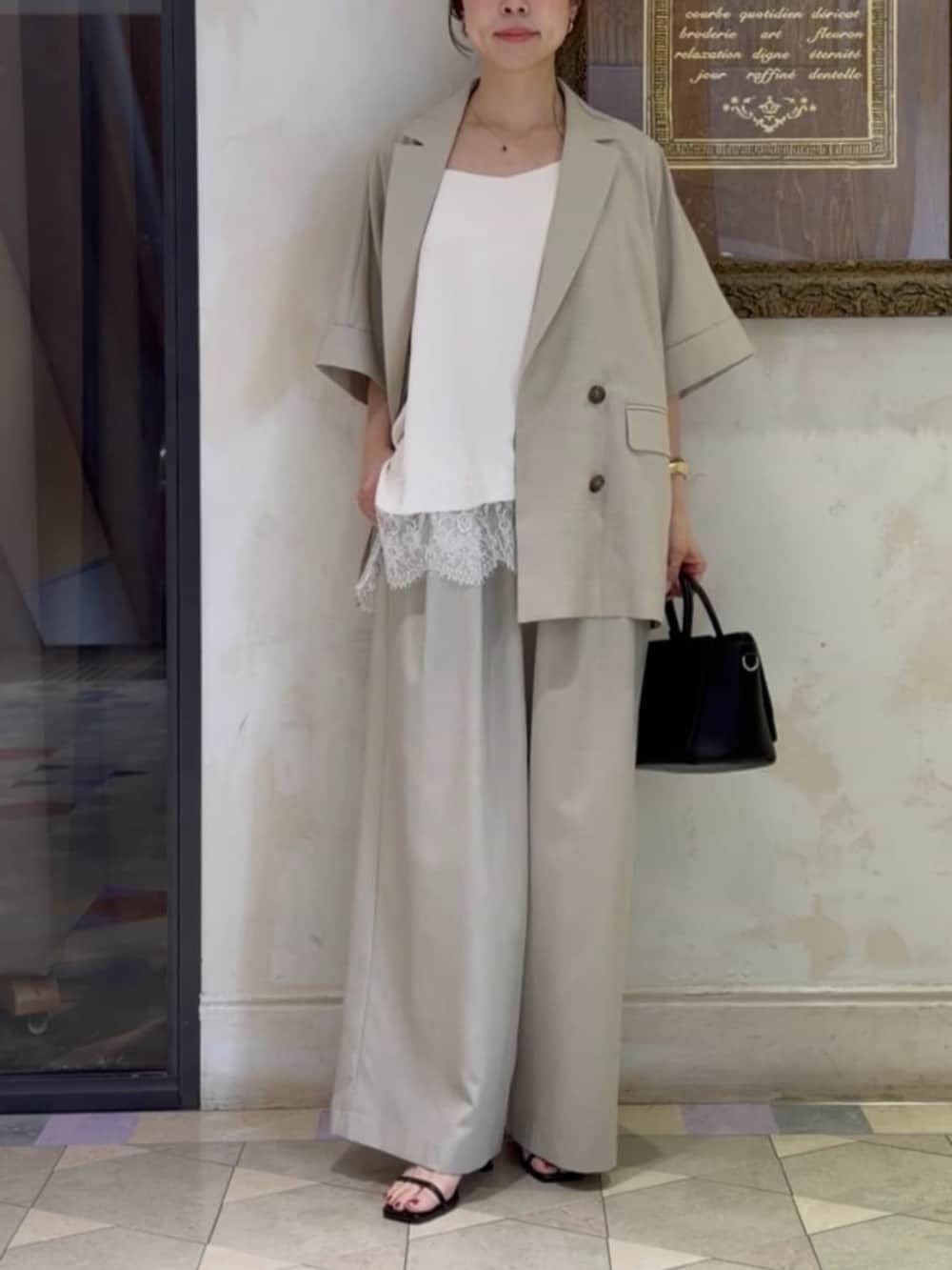 ブラック系のハンドバッグ、ベージュ系のテーラードジャケット、ホワイト系のキャミソールを着用したレディースの春コーディネートの4枚目の写真