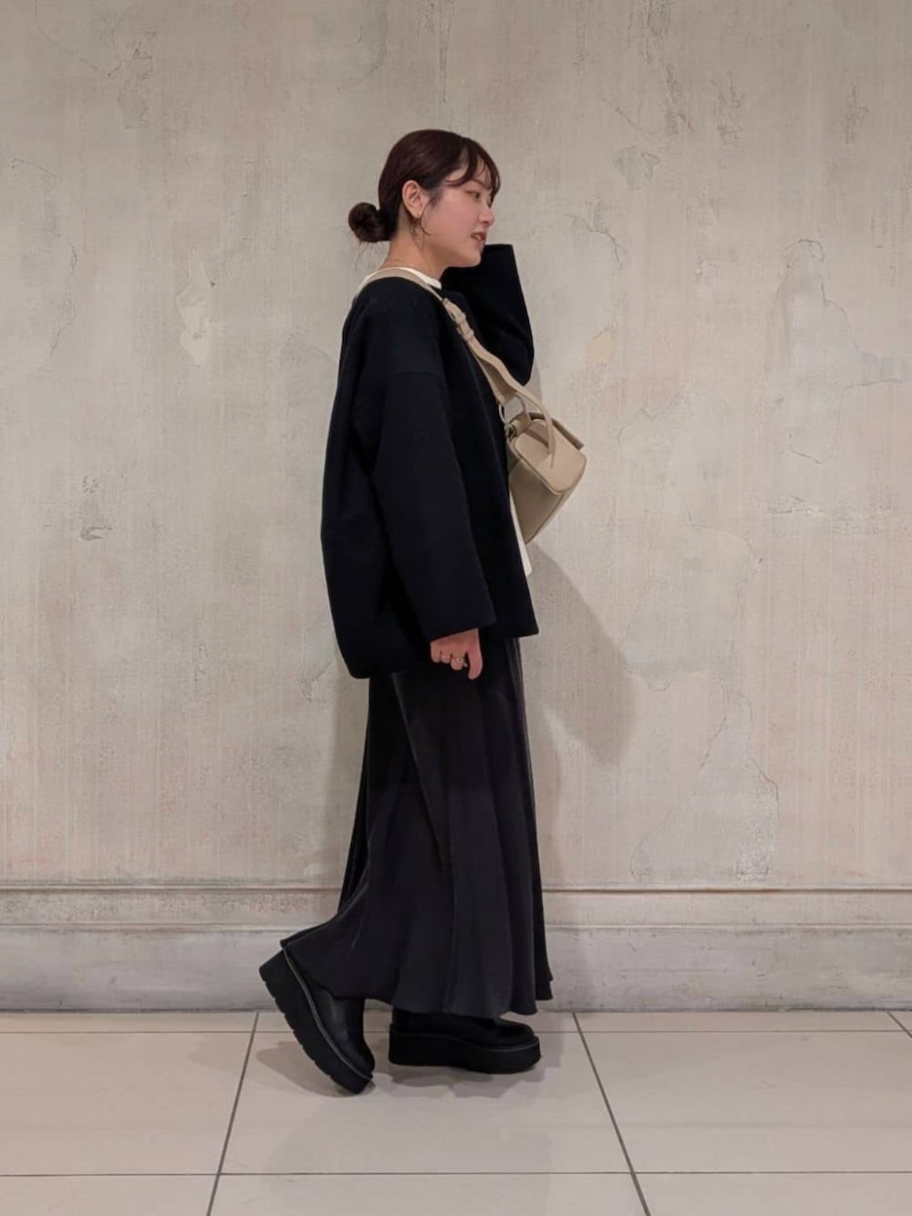 ブラック系のスカート、ブラック系のブーツ、ブルー系のノーカラーコートを着用したレディースの冬コーディネートの2枚目の写真