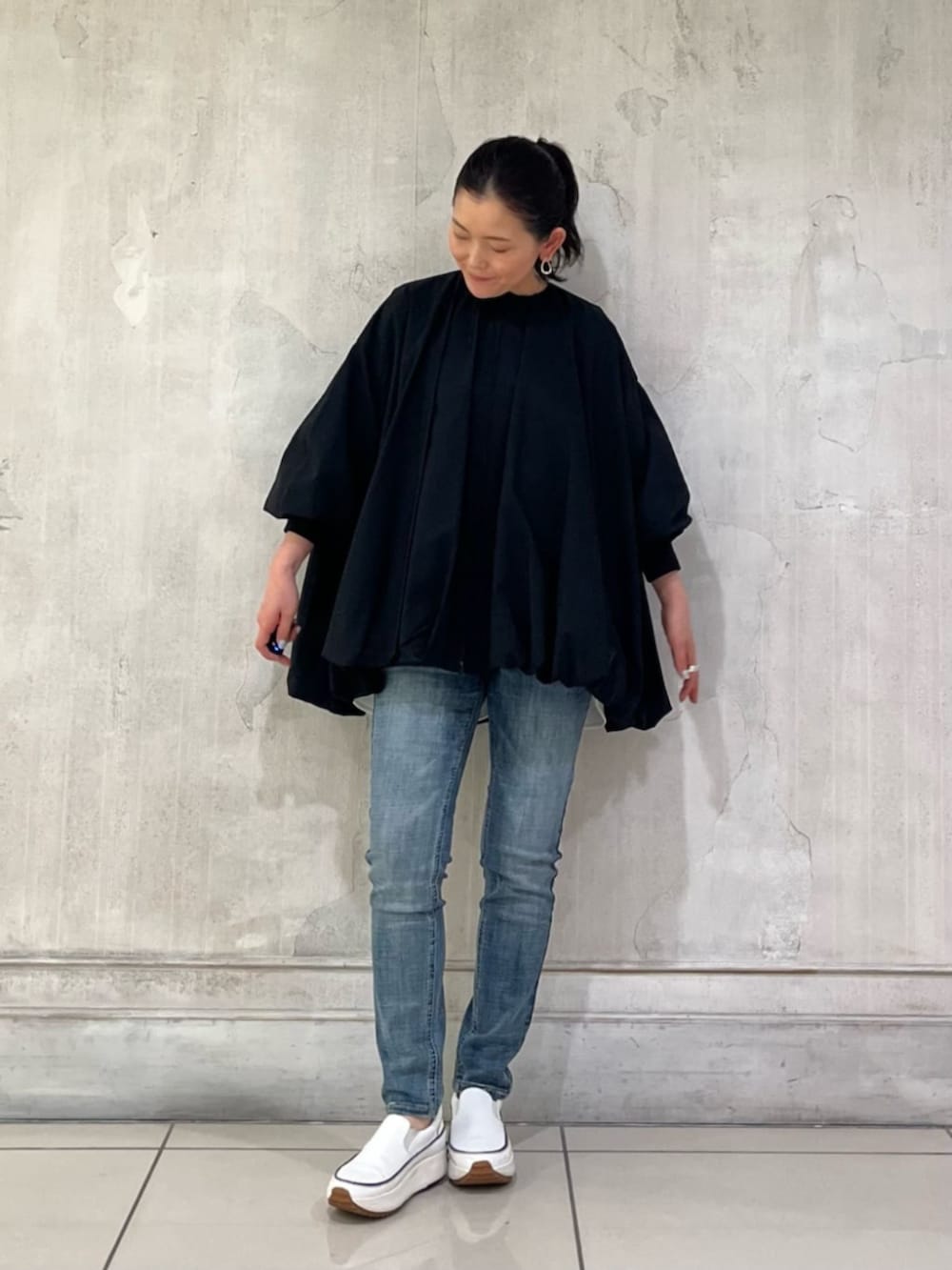 ホワイト系のスニーカー、ブルー系のデニムパンツ、ブラック系のボストンバッグを着用したレディースの冬コーディネートの4枚目の写真