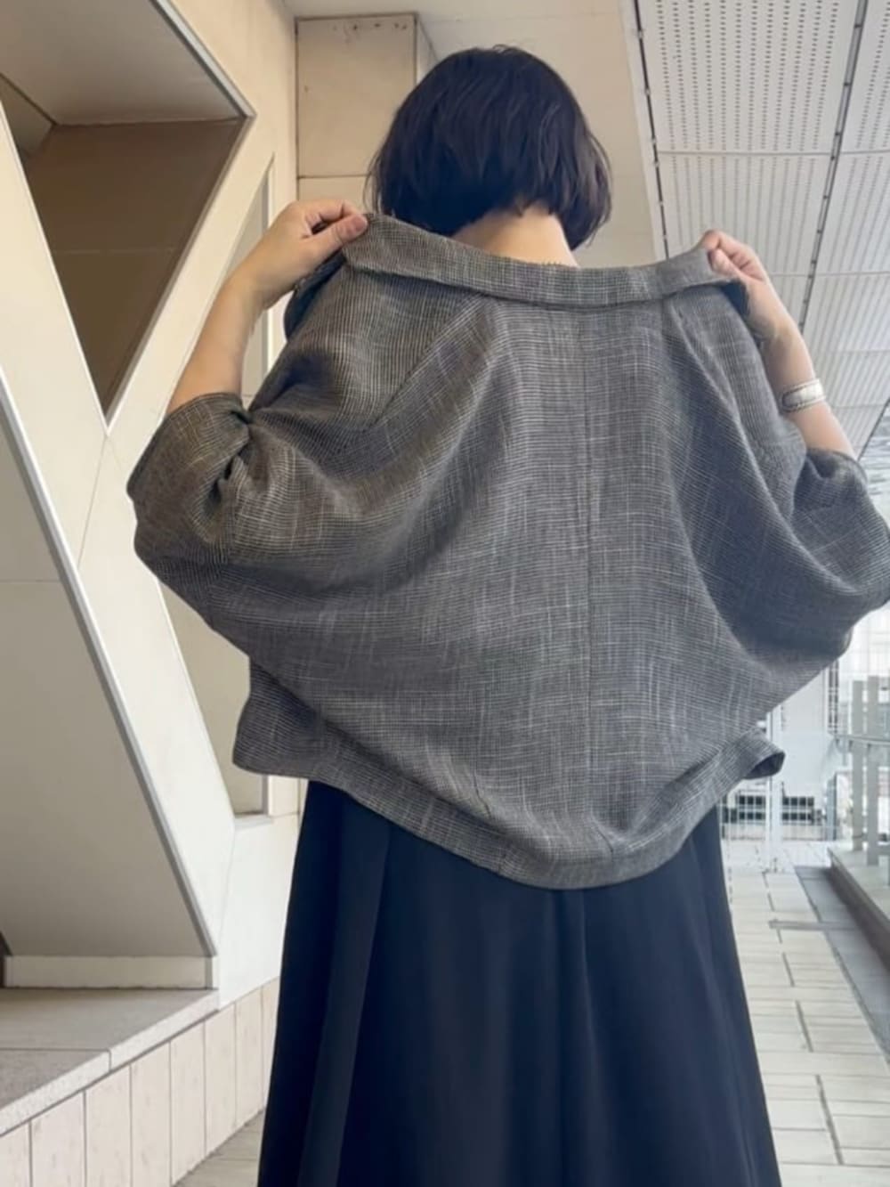 ベージュ系のテーラードジャケット、ブラック系のワンピース、ブラック系のスニーカーを着用したレディースの夏コーディネートの4枚目の写真