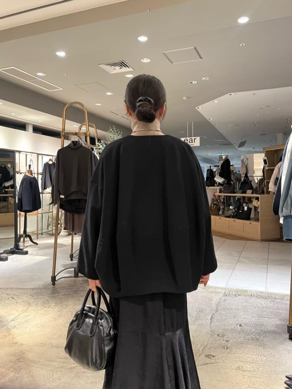 ブラック系のボストンバッグ、ブラック系のノーカラーコートを着用したレディースの冬コーディネートの5枚目の写真