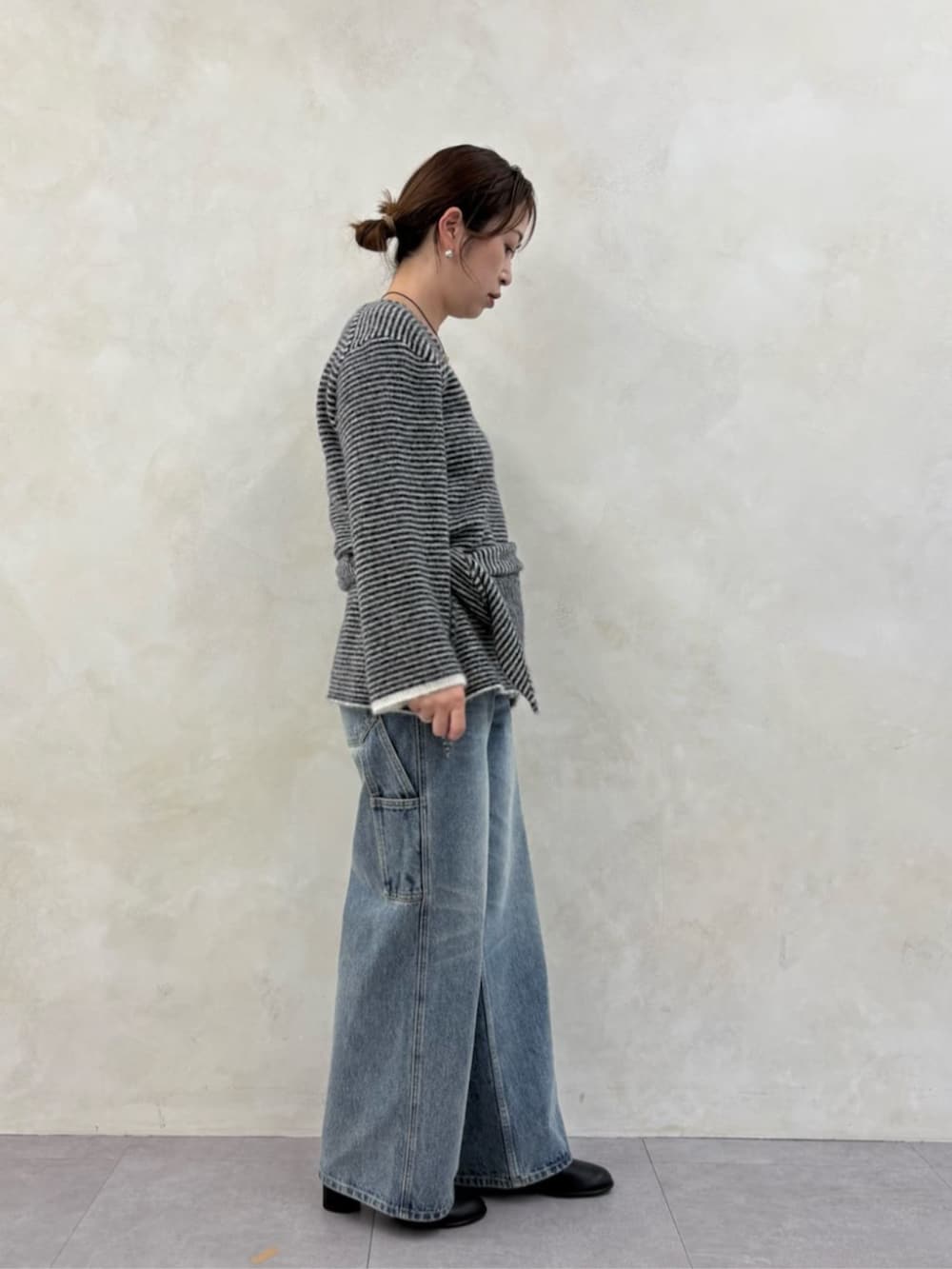 ブルー系のデニムパンツ、ブラック系のブーツ、ブラック系のニット/セーターを着用したレディースの秋コーディネートの6枚目の写真