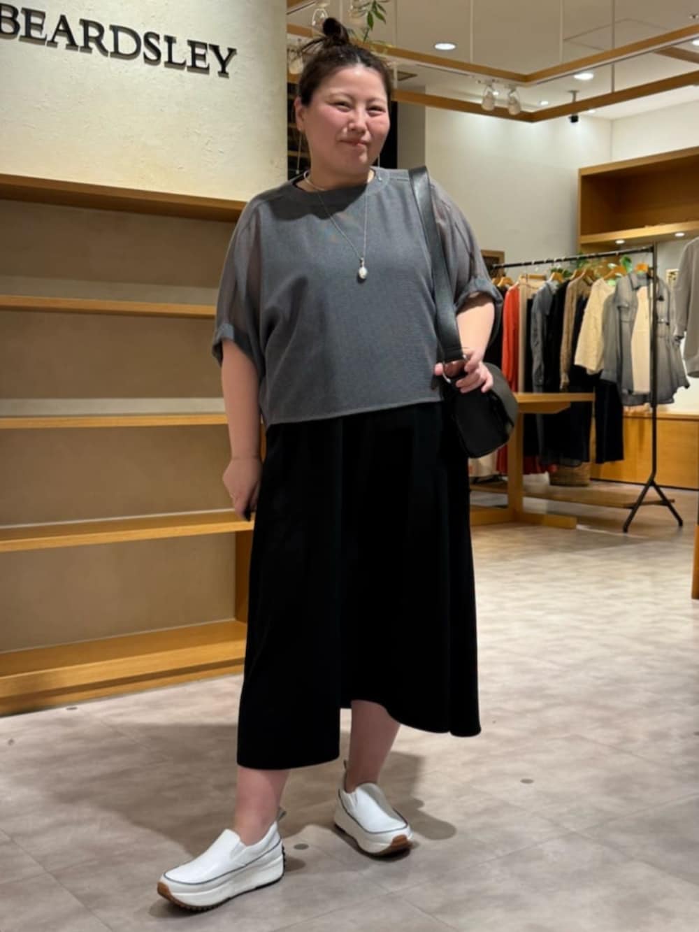 ホワイト系のスニーカー、ブラック系のワンピース、グレー系のTシャツ/カットソーを着用したレディースの夏コーディネートの2枚目の写真