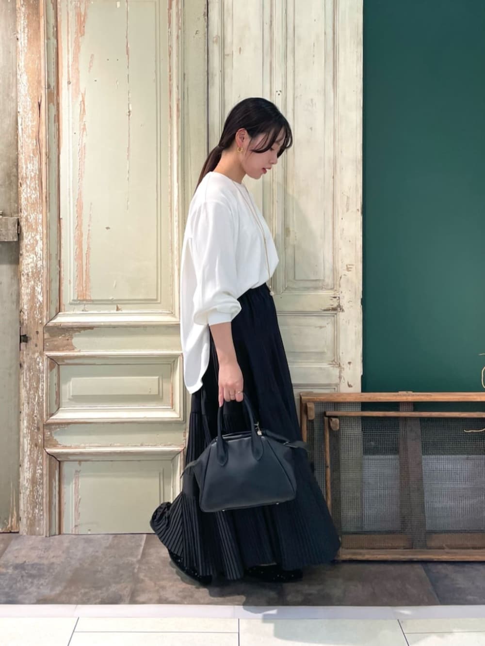 ブラック系のスカート、ホワイト系のシャツ/ブラウスを着用したレディースの春コーディネートの2枚目の写真