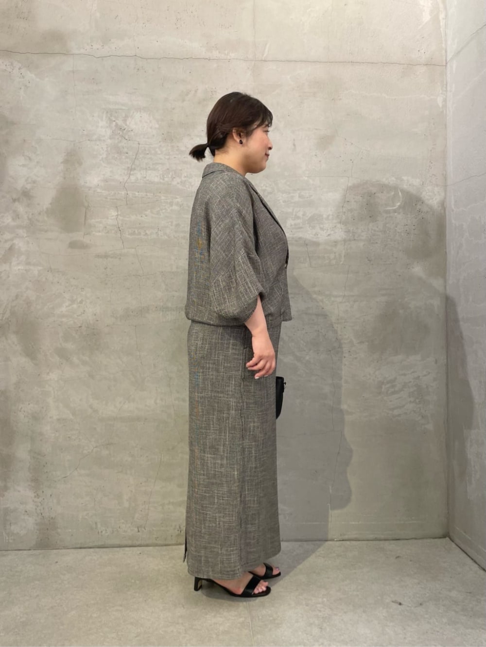 ブラック系のハンドバッグ、ベージュ系のテーラードジャケット、ベージュ系のスカートを着用したレディースの春コーディネートの2枚目の写真