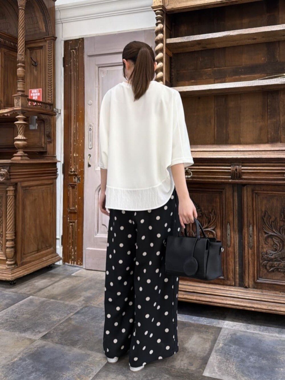ブラック系のハンドバッグ、ブラック系のその他パンツ、ホワイト系のTシャツ/カットソーを着用したレディースの春コーディネートの2枚目の写真