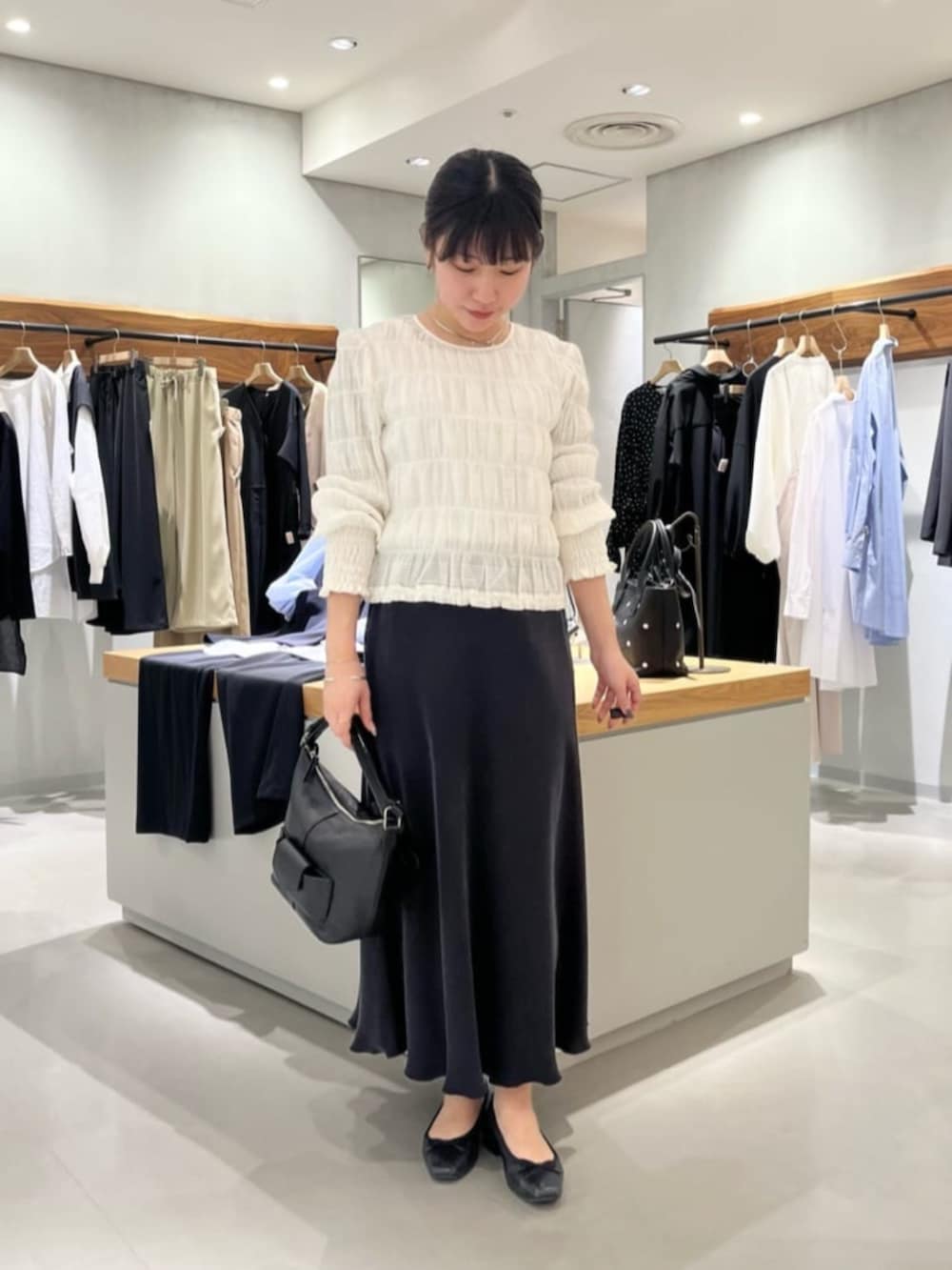 ブラック系のスカート、ブラック系のトートバッグ、ホワイト系のシャツ/ブラウスを着用したレディースの春コーディネートの4枚目の写真