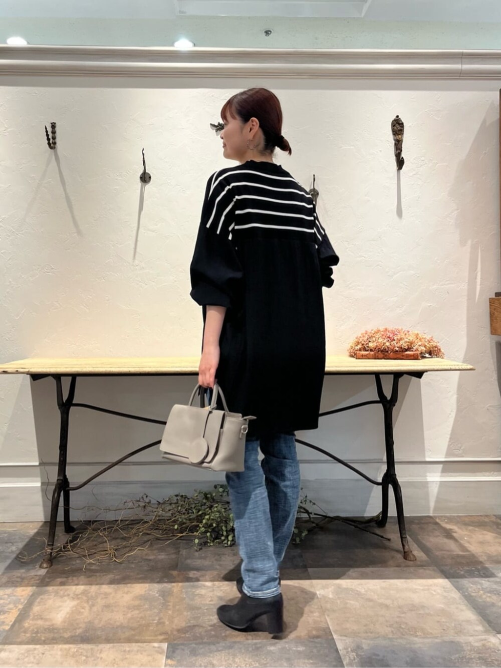 ブルー系のデニムパンツ、グレー系のハンドバッグ、ブラック系のニット/セーターを着用したレディースの冬コーディネートの2枚目の写真