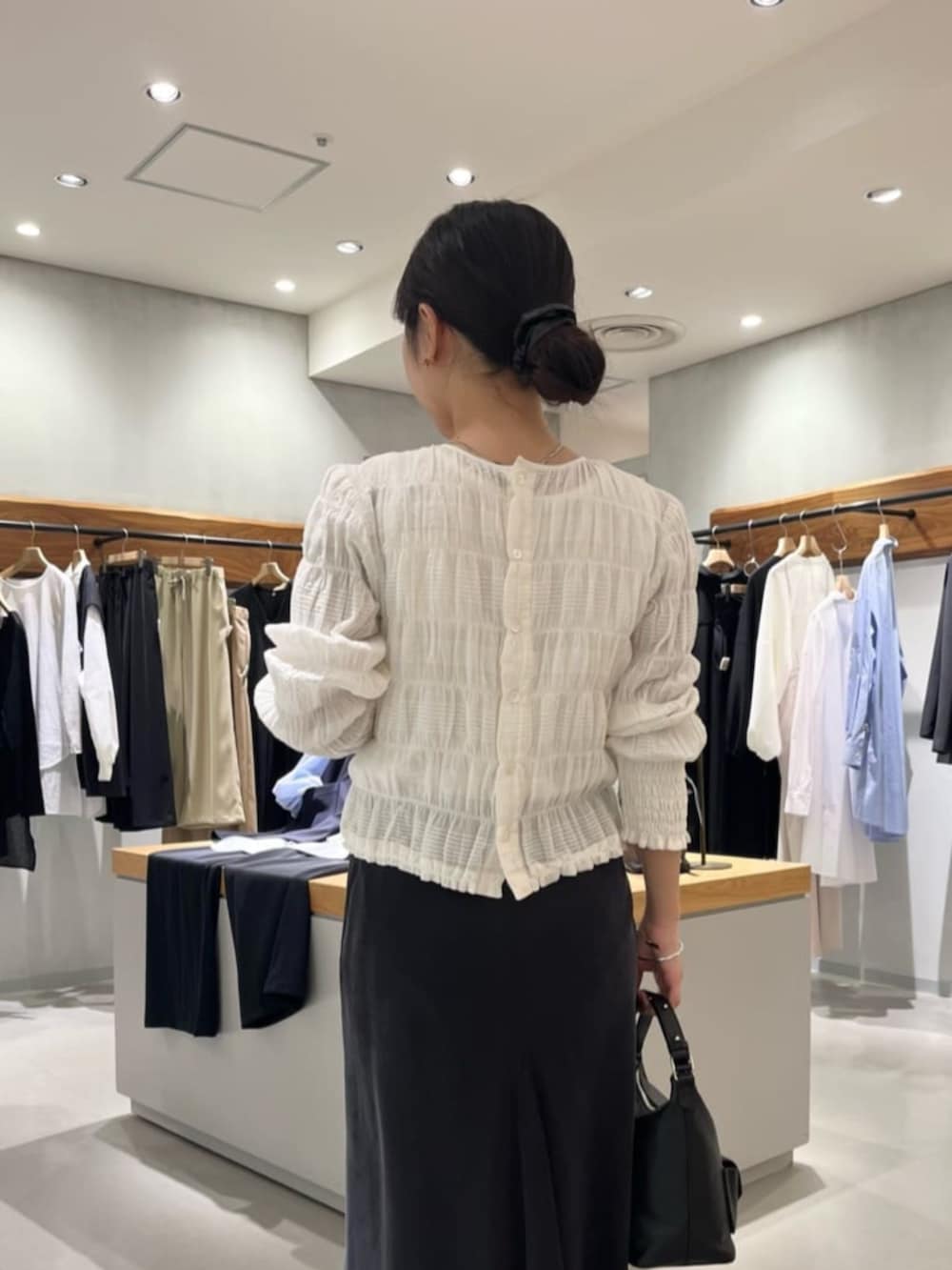 ブラック系のスカート、ブラック系のトートバッグ、ホワイト系のシャツ/ブラウスを着用したレディースの春コーディネートの6枚目の写真