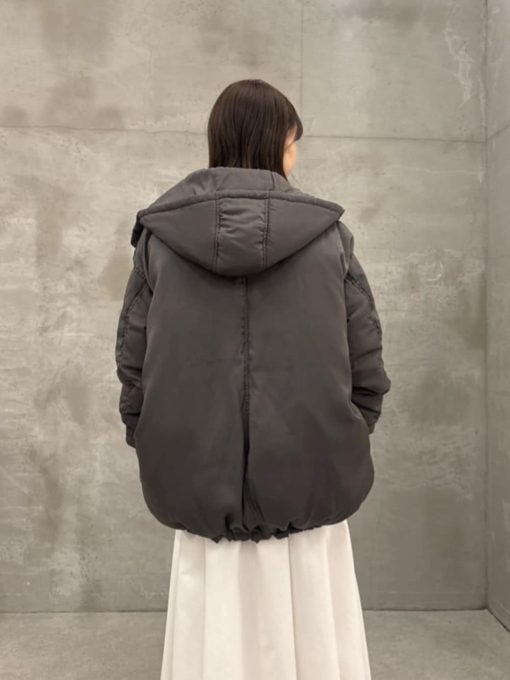 ホワイト系のスカート、グレー系のダウンジャケット/コート、グレー系のTシャツ/カットソーを着用したレディースの秋コーディネートの6枚目の写真