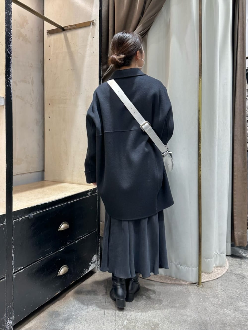 ブラック系のスカート、ブルー系のピーコート、シルバー系のショルダーバッグを着用したレディースの冬コーディネートの3枚目の写真