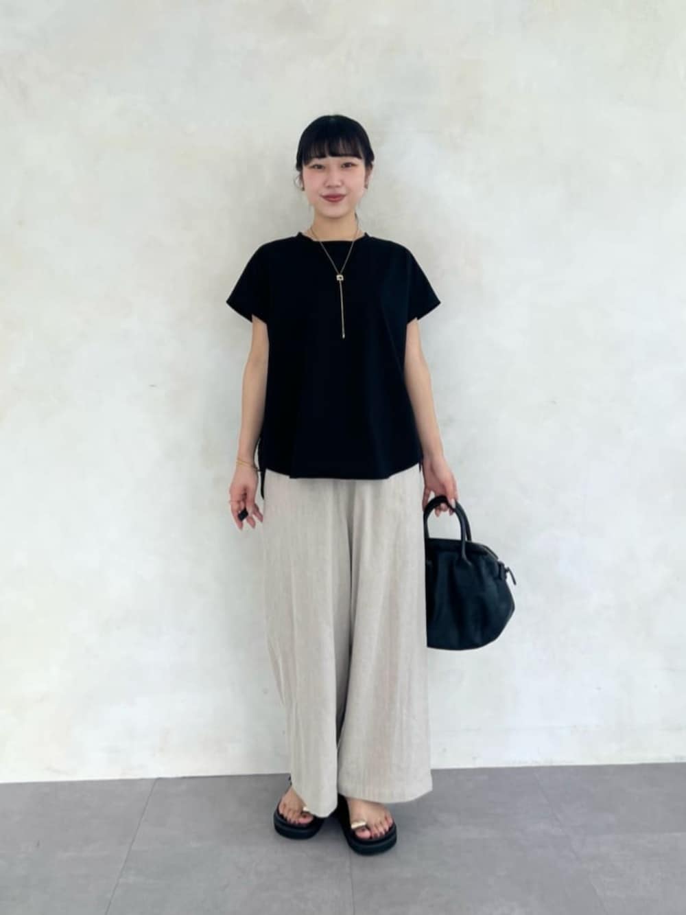 ベージュ系のその他パンツ、ブラック系のTシャツ/カットソー、ブラック系のサンダルを着用したレディースの春コーディネートの4枚目の写真