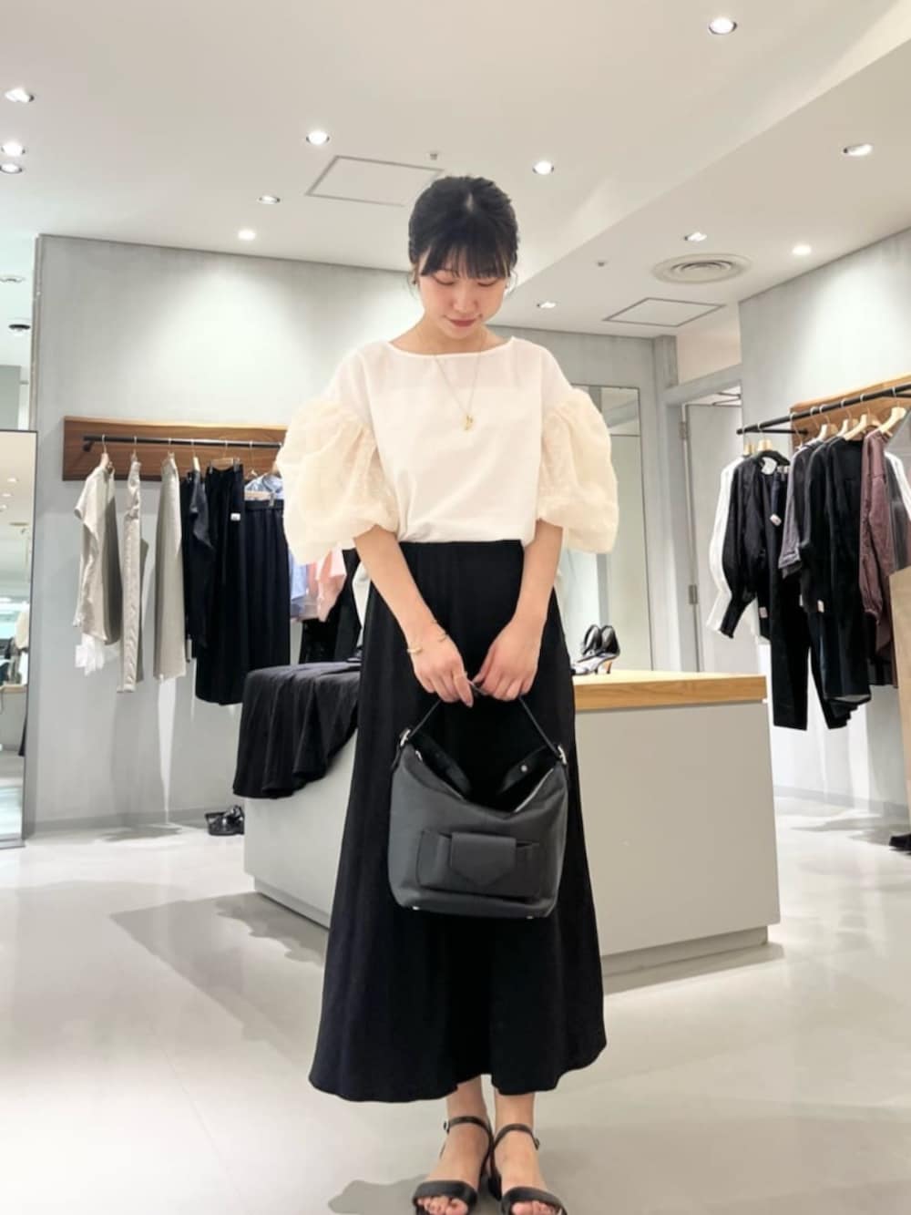 ブラック系のスカート、ホワイト系のシャツ/ブラウスを着用したレディースの夏コーディネートの7枚目の写真