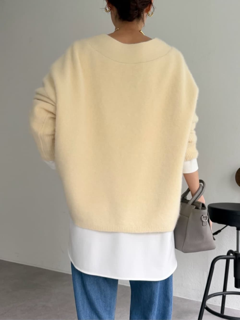 グレー系のハンドバッグ、ホワイト系のシャツ/ブラウス、イエロー系のニット/セーターを着用したレディースの秋コーディネートの5枚目の写真