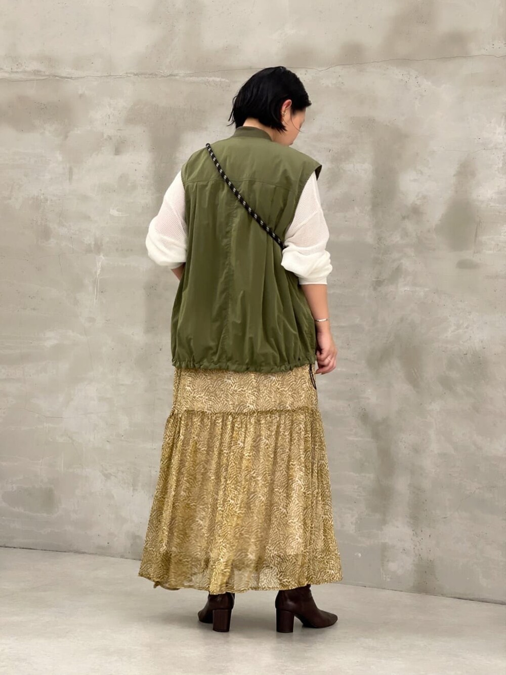 ホワイト系のTシャツ/カットソー、グリーン系のベスト、ベージュ系のスカートを着用したレディースの夏コーディネートの3枚目の写真