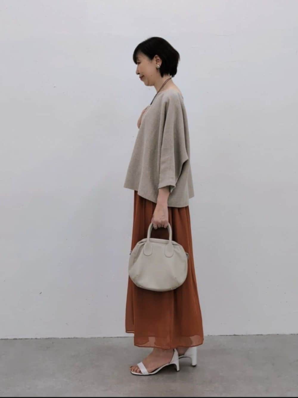 グレー系のボストンバッグ、オレンジ系のその他パンツ、ベージュ系のニット/セーターを着用したレディースの冬コーディネートの3枚目の写真