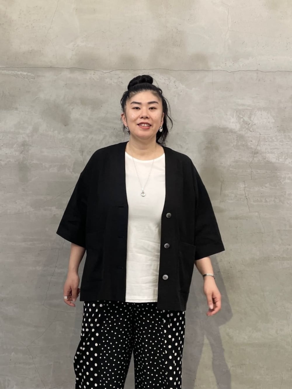 ホワイト系のタンクトップ、ブラック系のボストンバッグ、ブラック系のサンダルを着用したレディースの春コーディネートの4枚目の写真