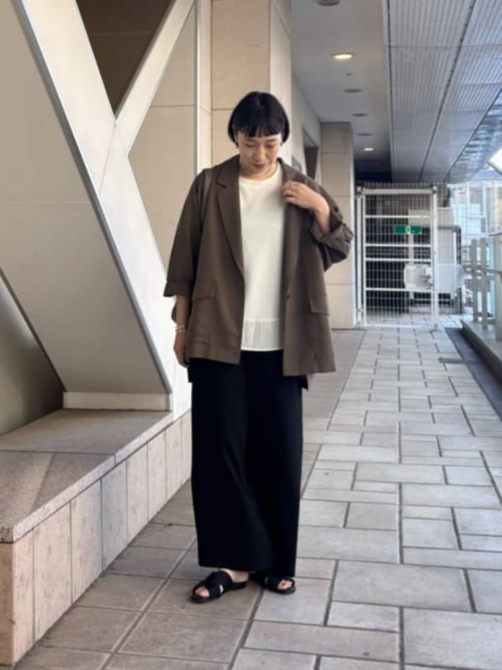 ブラック系のその他パンツ、ブラウン系のテーラードジャケット、ホワイト系のTシャツ/カットソーを着用したレディースの春コーディネートの2枚目の写真