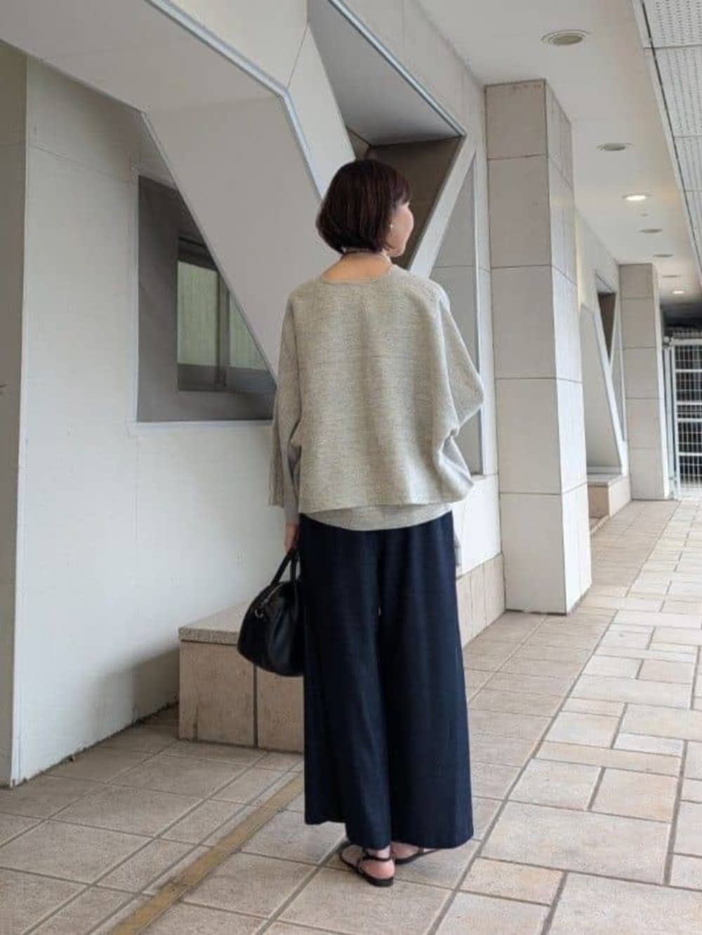 ブルー系のその他パンツ、ブラック系のボストンバッグ、グレー系のニット/セーターを着用したレディースの冬コーディネートの3枚目の写真