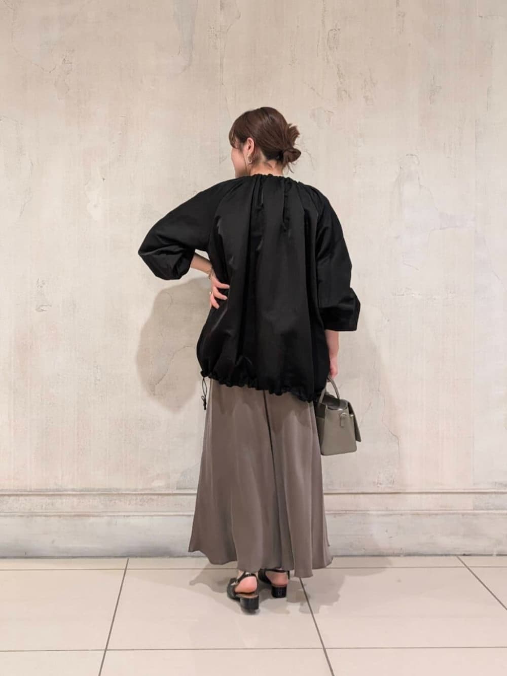 グリーン系のスカート、グレー系のハンドバッグ、ブラック系のノーカラージャケットを着用したレディースの春コーディネートの7枚目の写真