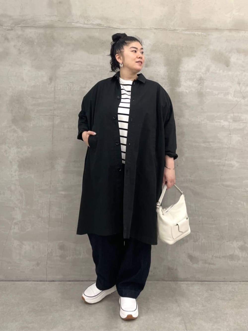 ホワイト系のトートバッグ、ブルー系のデニムパンツ、ブラック系のその他アウターを着用したレディースの冬コーディネートの2枚目の写真