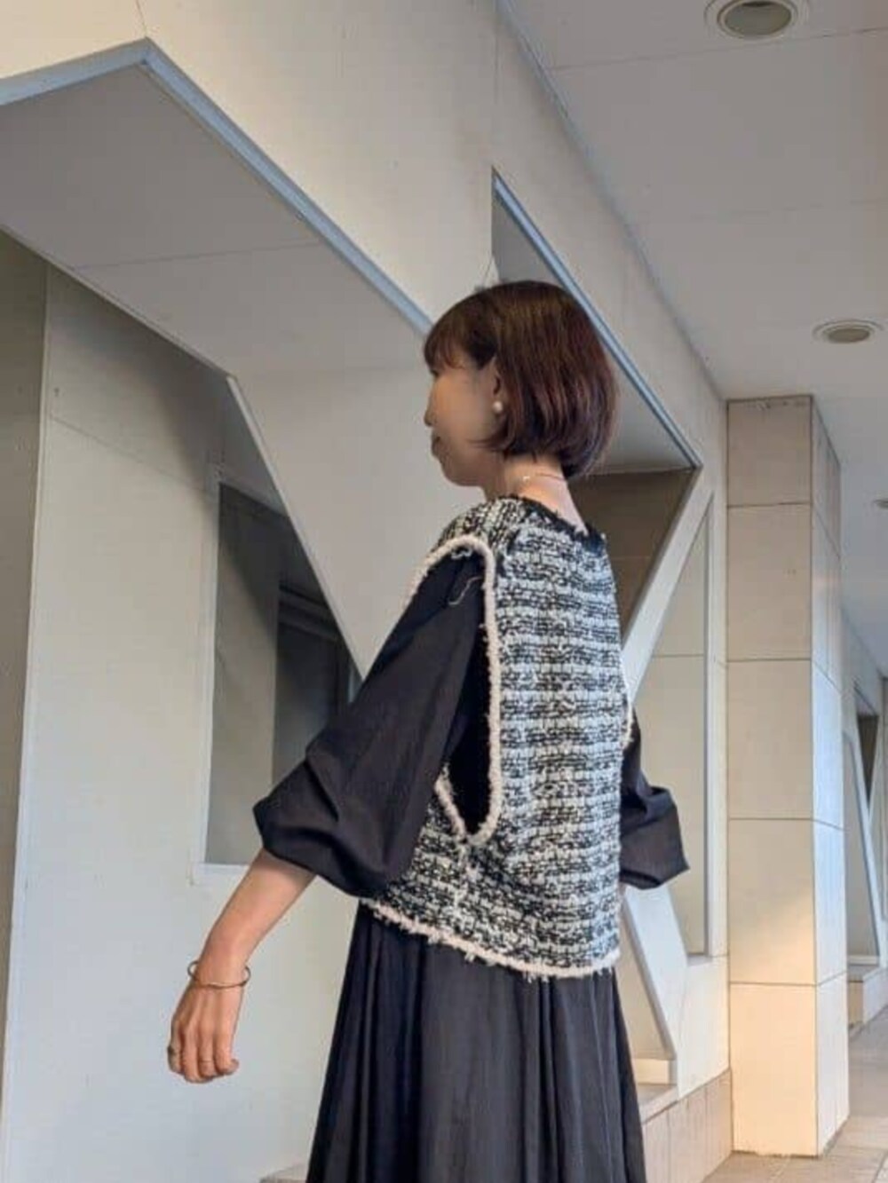 ベージュ系のショルダーバッグ、ブラック系のベスト、ブラック系のワンピースを着用したレディースの冬コーディネートの4枚目の写真